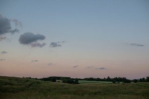 夏の日没時に緑の田園地帯の丘を転がる写真 