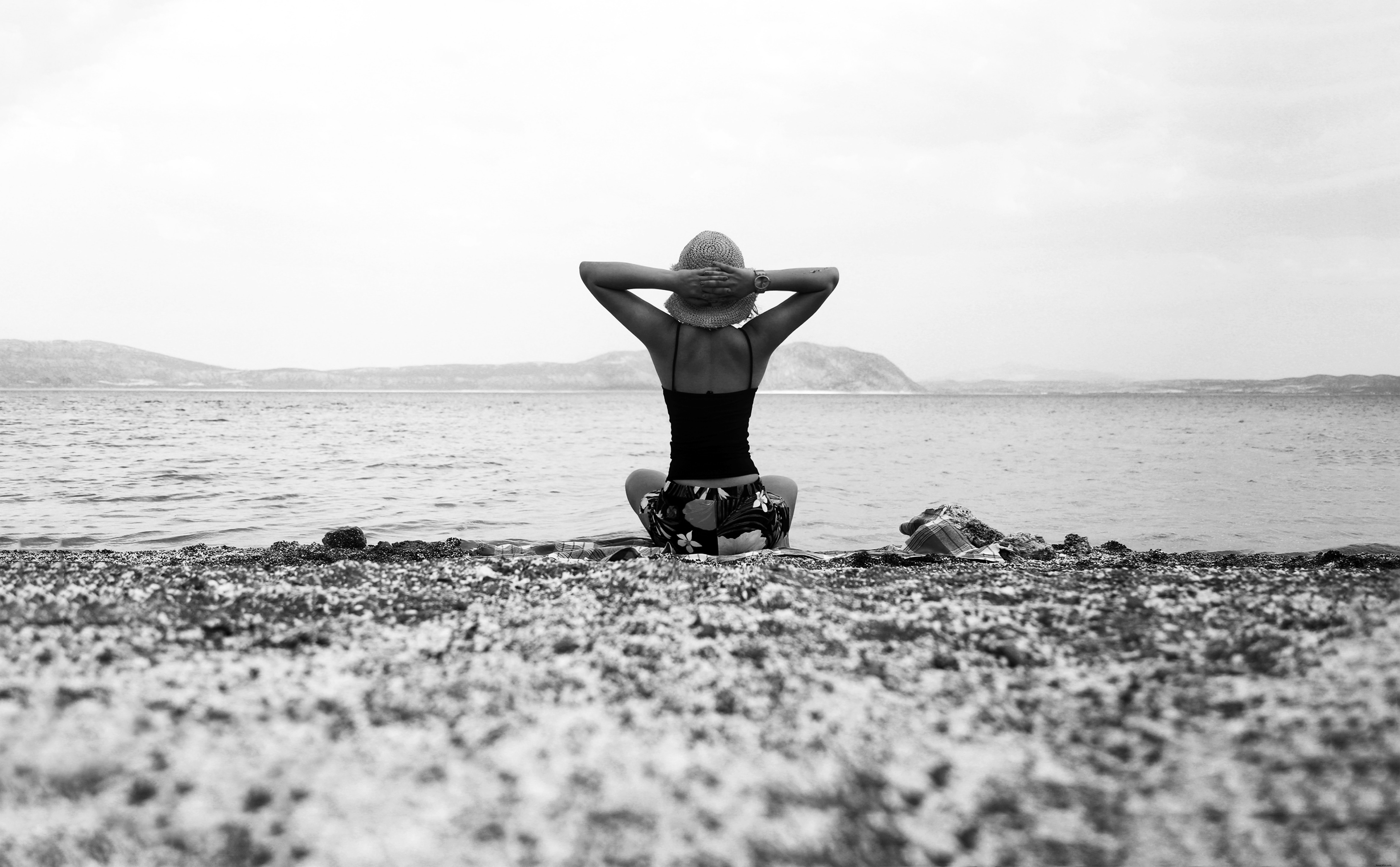 Pessoa em uma praia com as mãos para cima em foto preto e branco 
