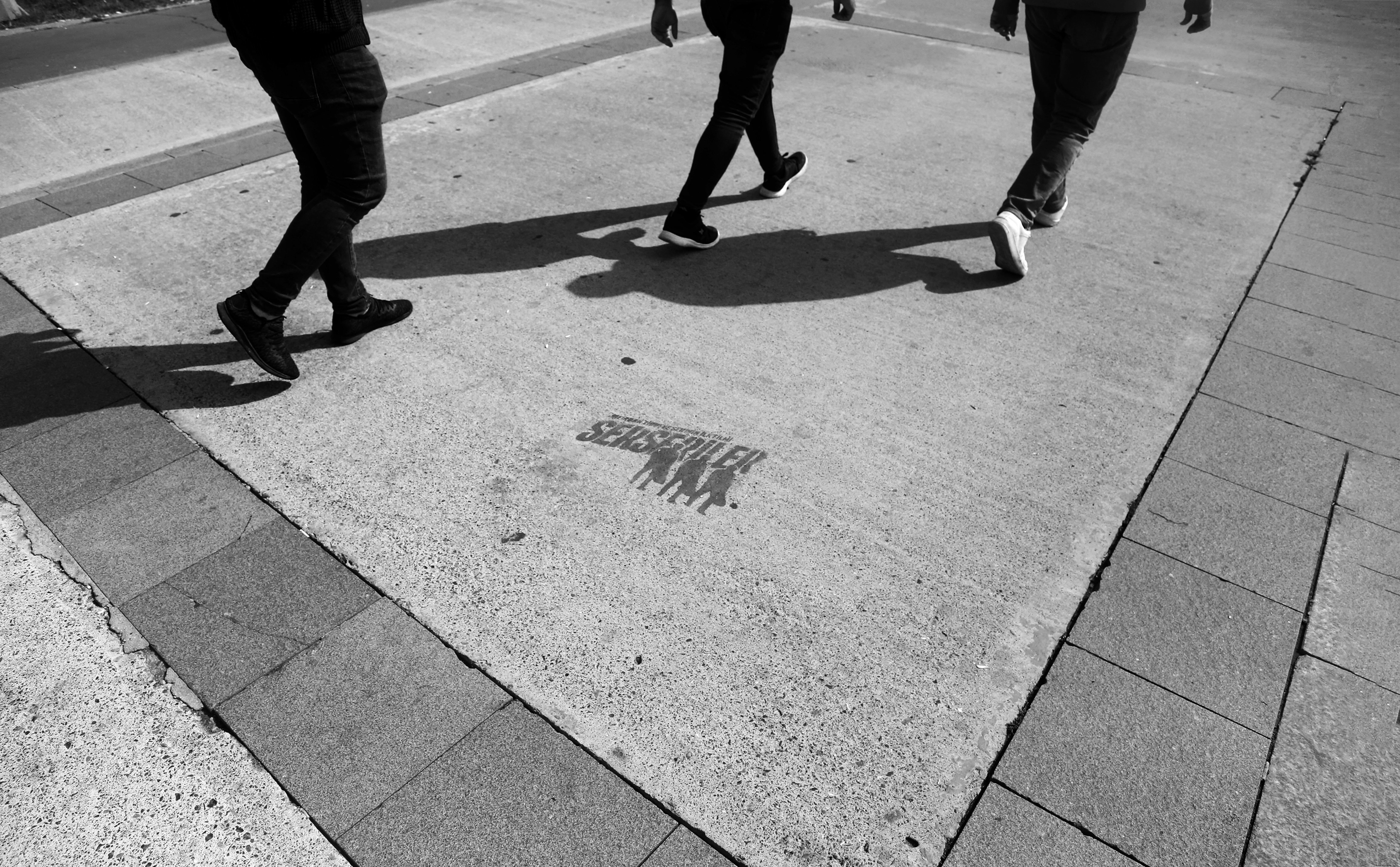 Pernas de três pessoas caminhando em fotos em preto e branco 