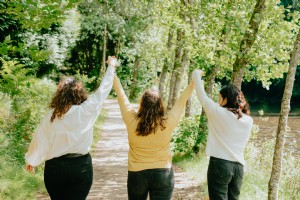 Tre persone con le mani alzate su un sentiero nel bosco Foto 