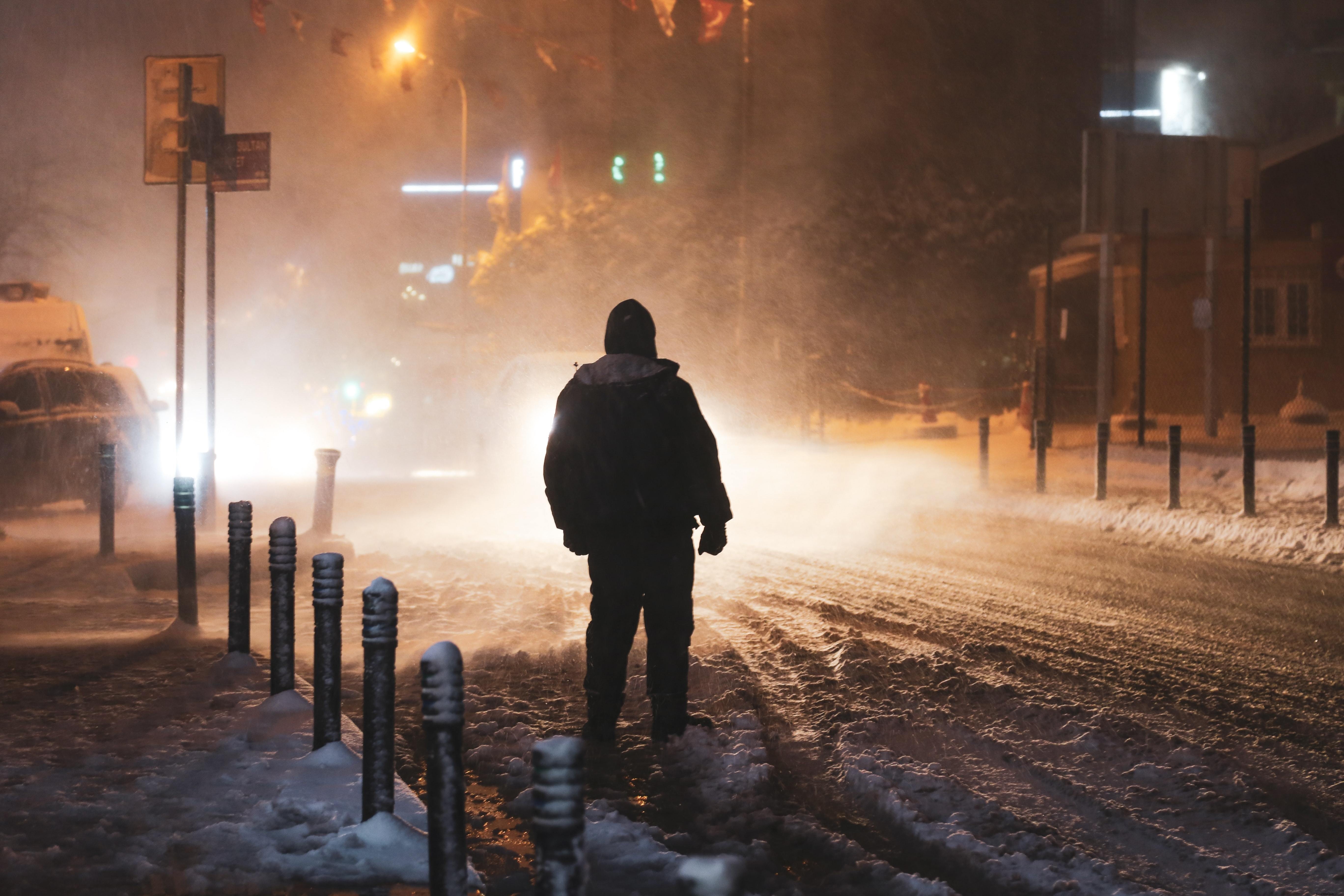 Persona iluminada por las luces de la calle durante una tormenta de nieve Foto 