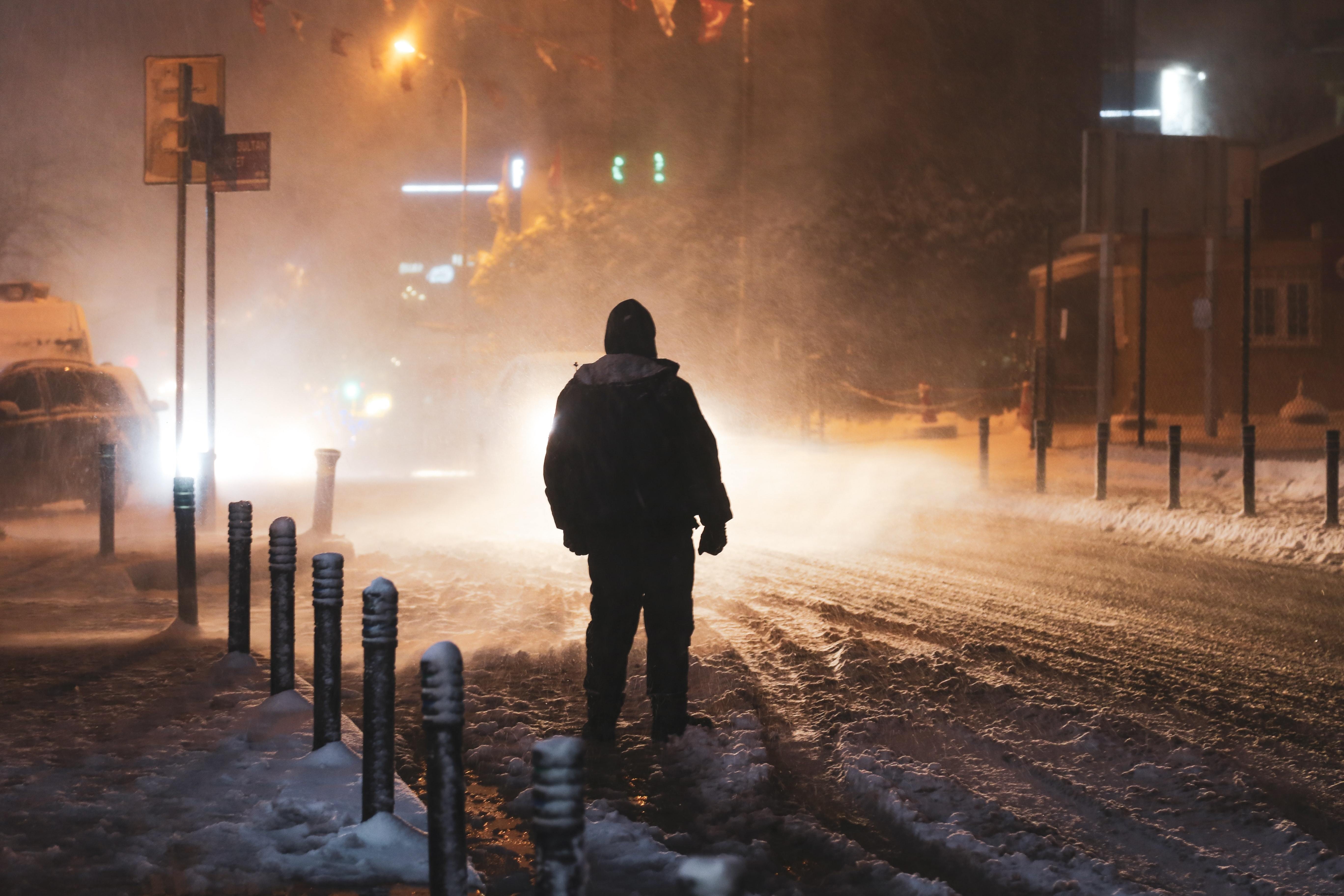 Pessoa iluminada pelas luzes da rua durante uma tempestade de neve Foto 