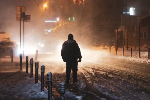 Pessoa iluminada pelas luzes da rua durante uma tempestade de neve Foto 