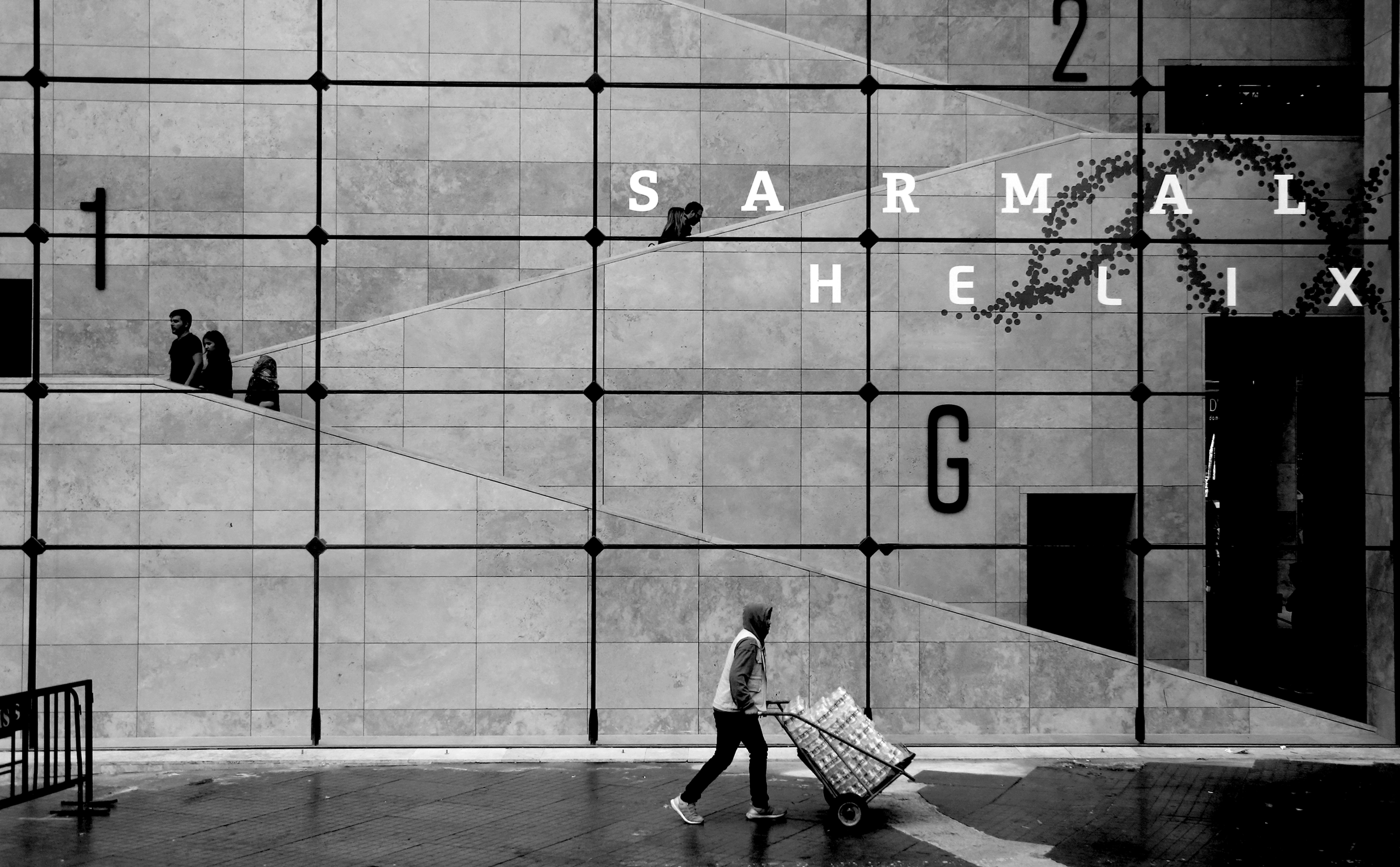 Pessoa passando por uma grande janela de grade em foto em preto e branco 