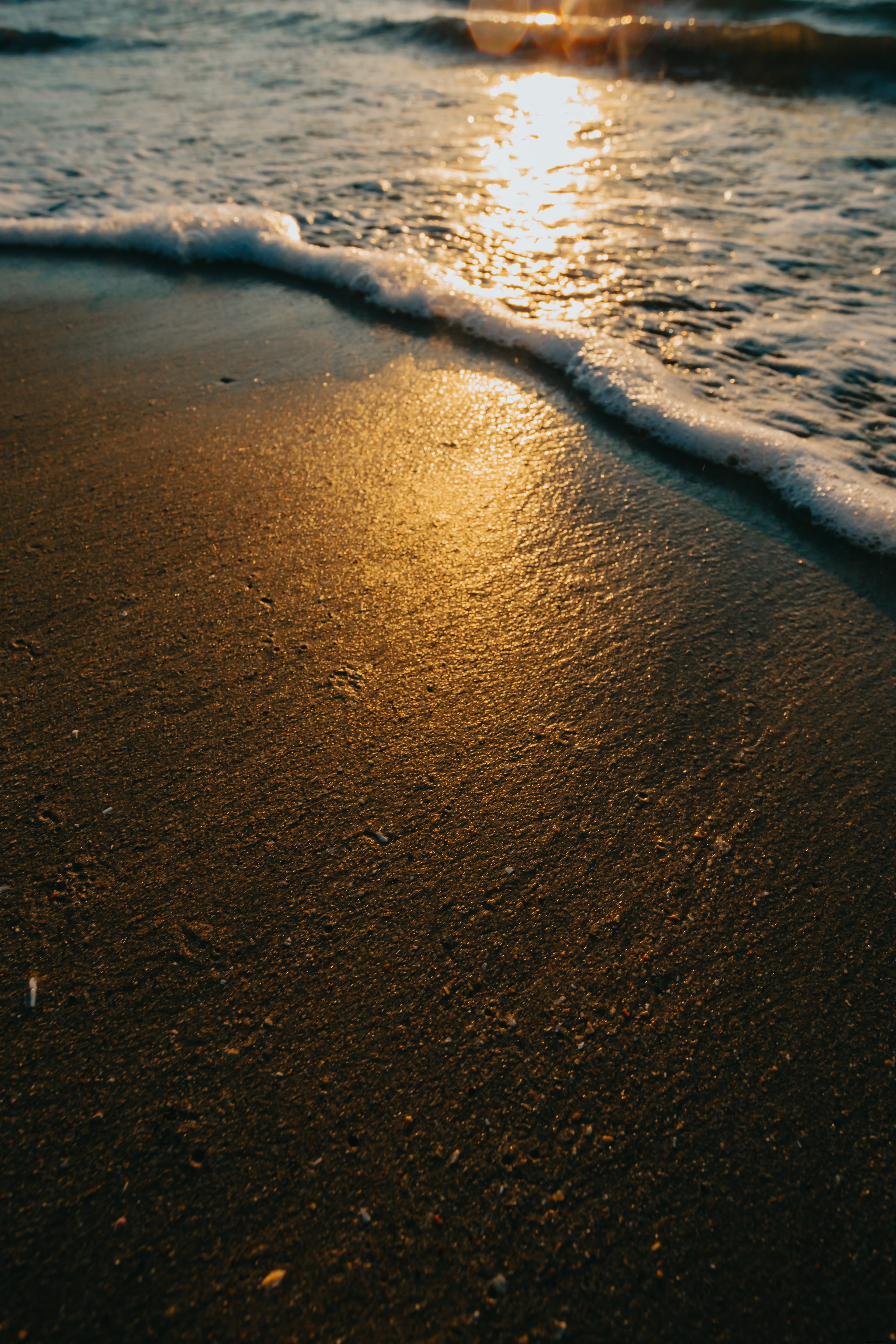 波が重なり合う砂浜の黄金の光写真 