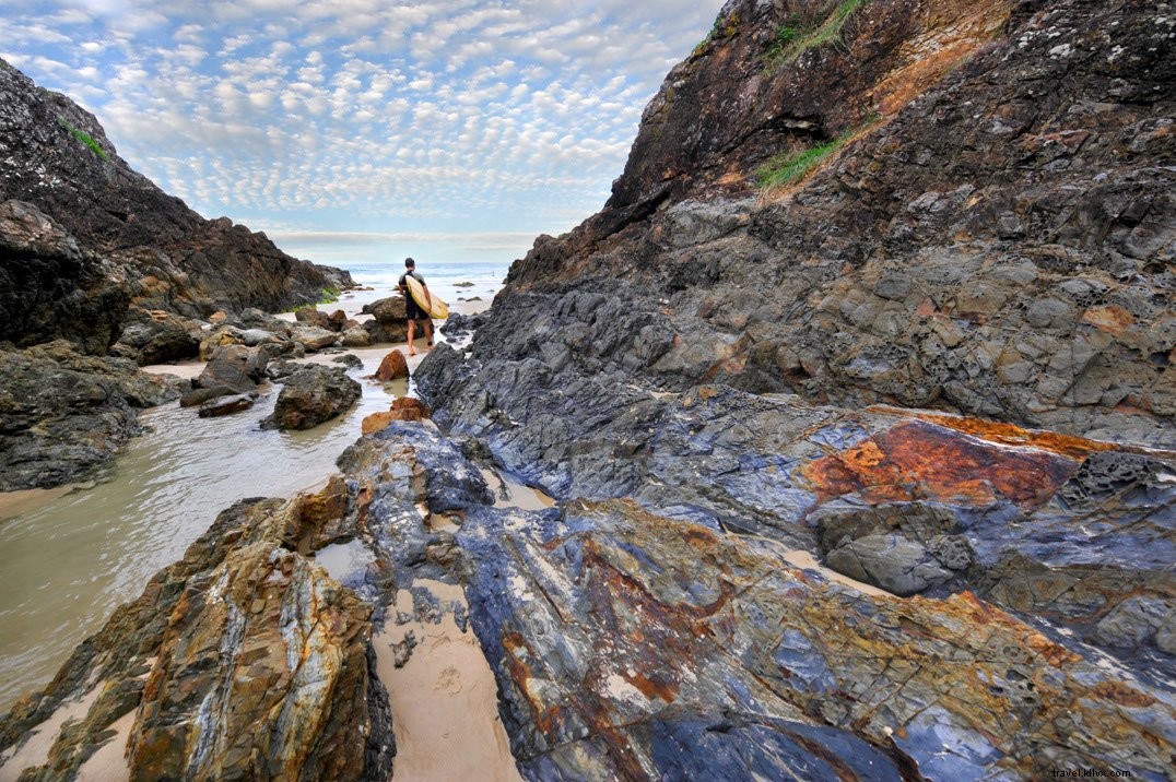 Garis Pantai Berbatu Dengan Seseorang Memegang Foto Papan Selancar 