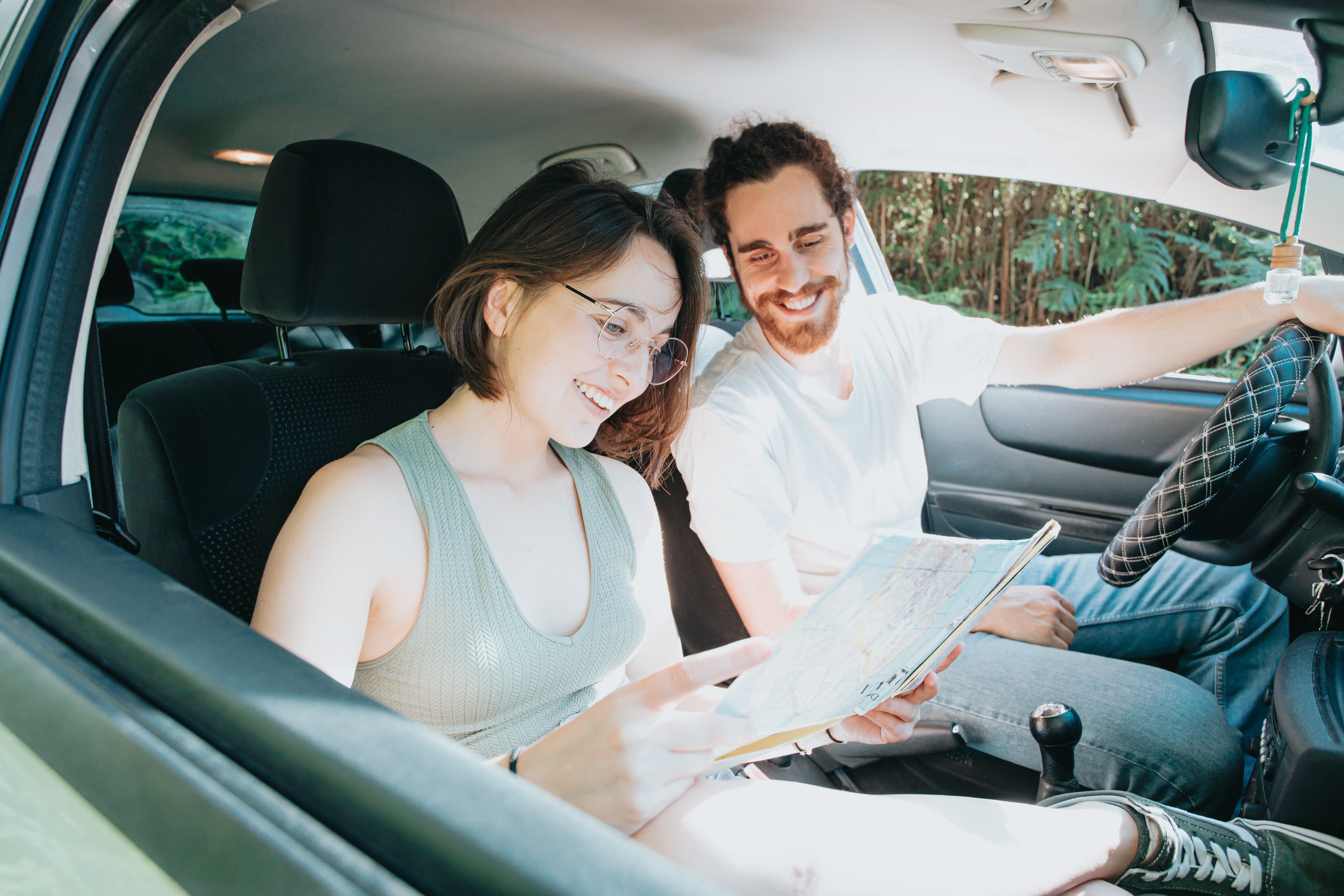 Deux personnes dans une voiture regardent une carte tout en souriant Photo 
