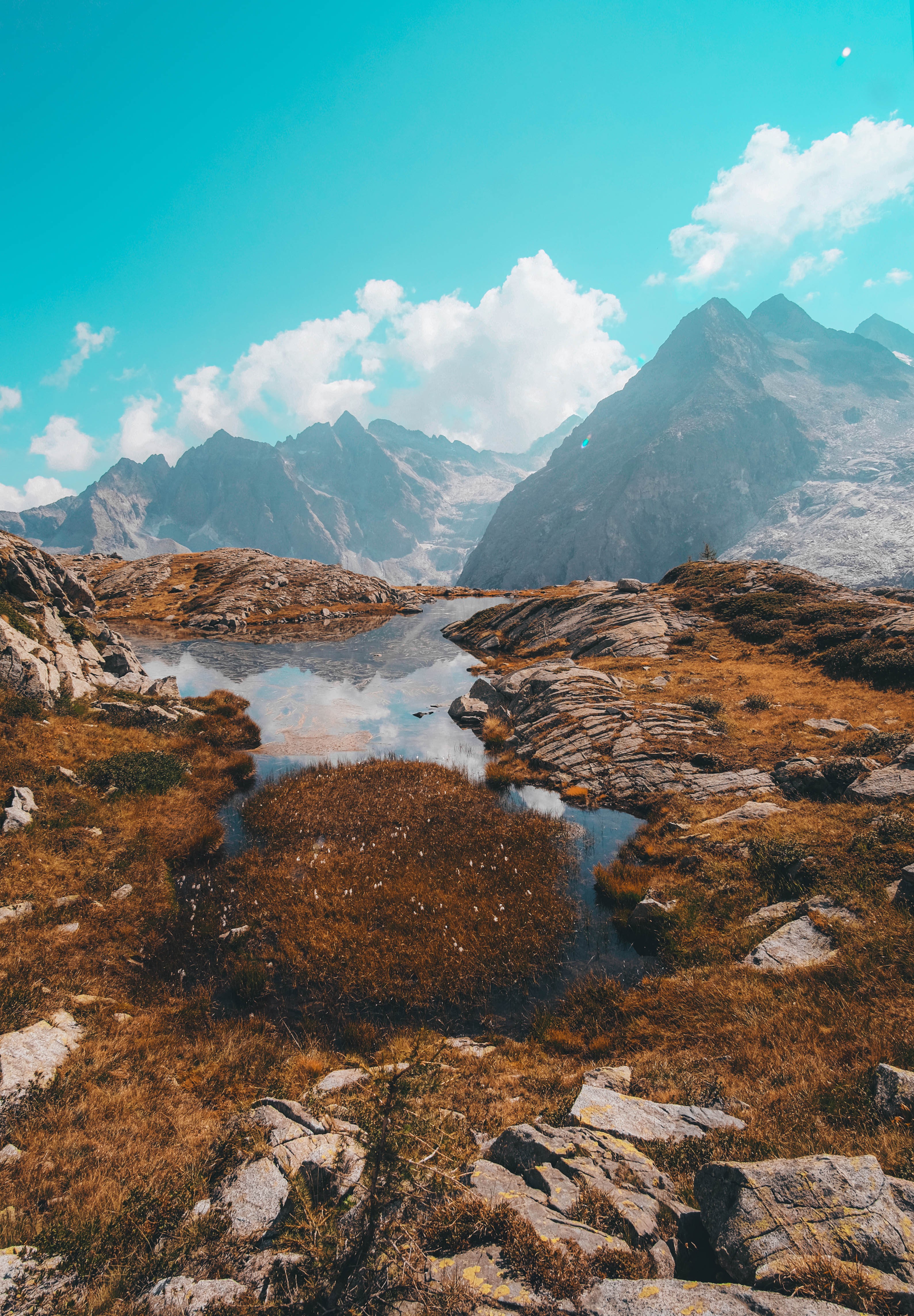 La cima de una colina rocosa refleja las montañas en una piscina de agua Foto 