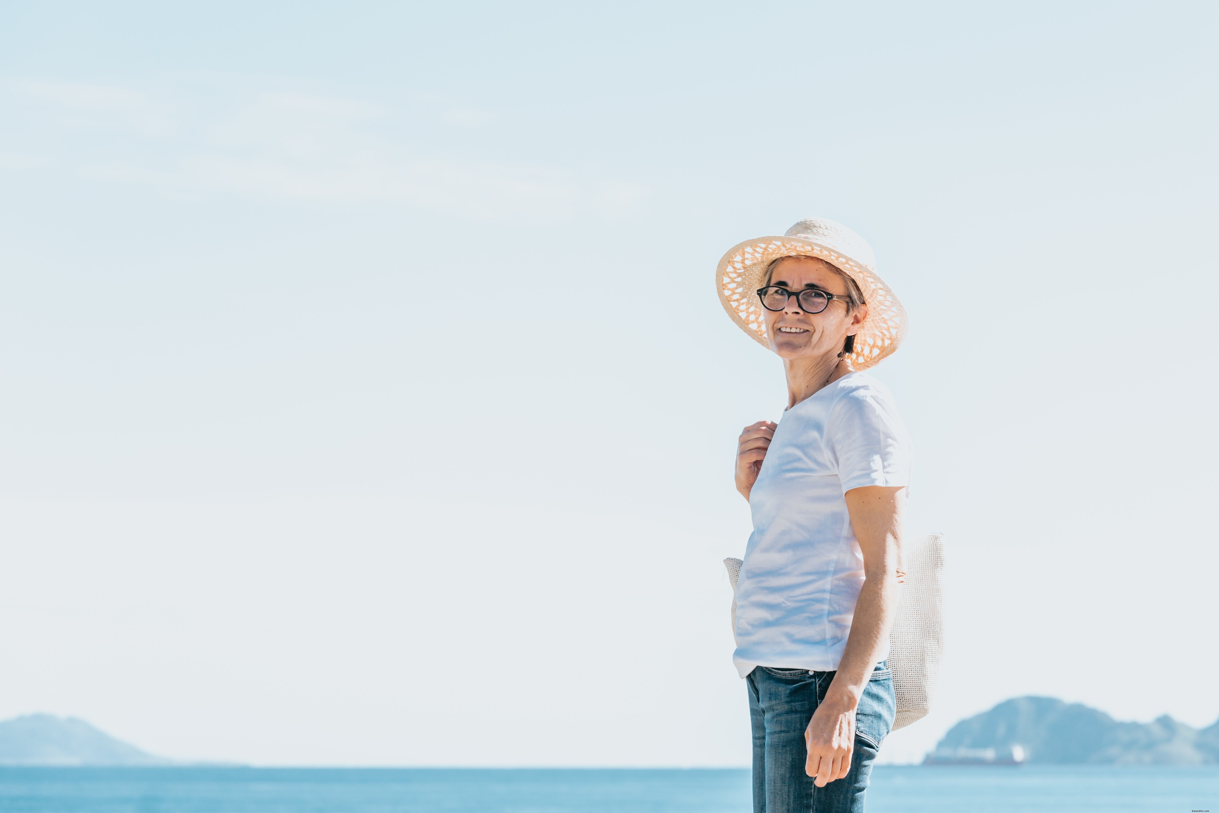 Mujer de pie junto a aguas abiertas y una foto de sombrero de paja 