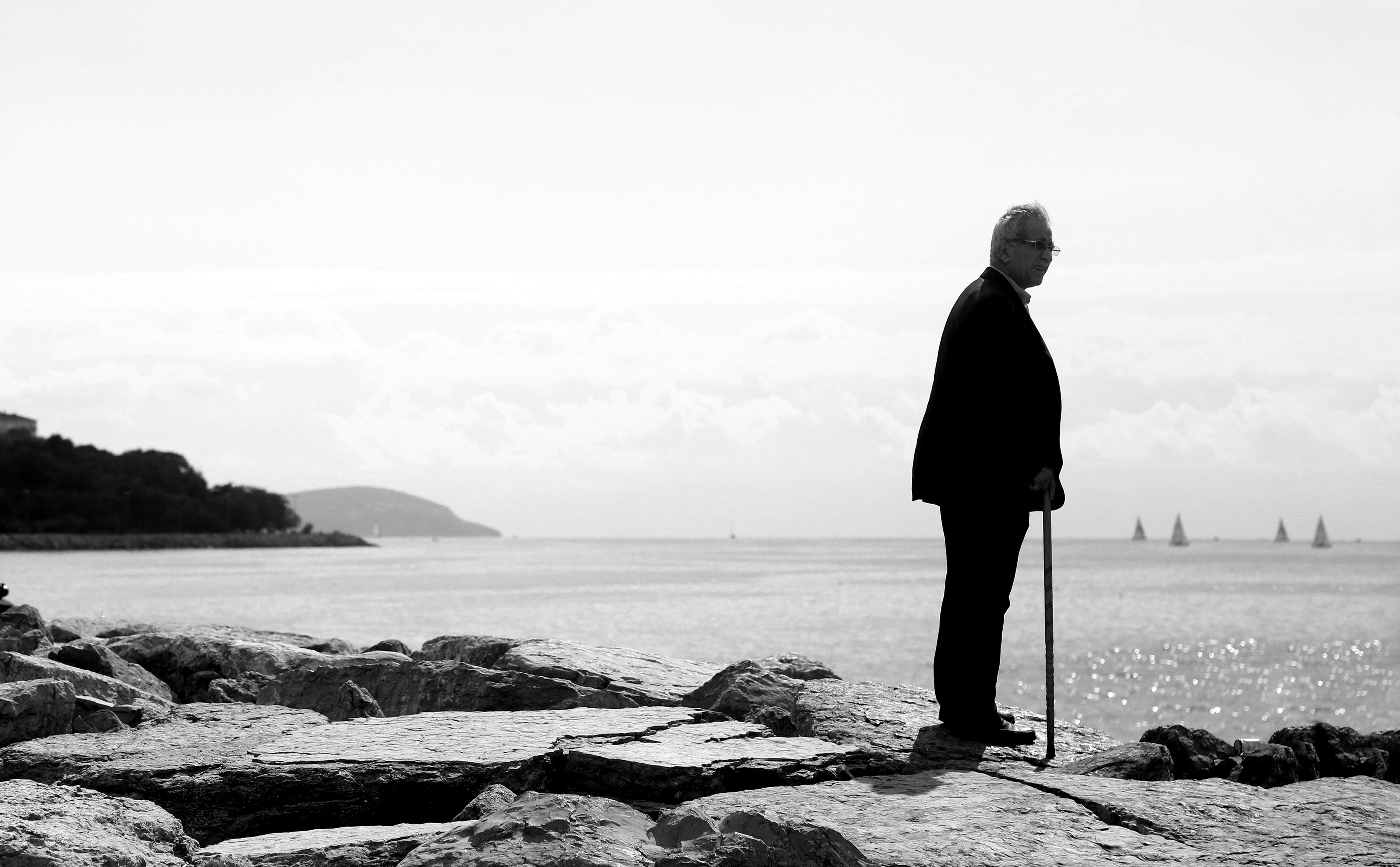 海岸の向こうに一人で立っているモノクロの男写真 