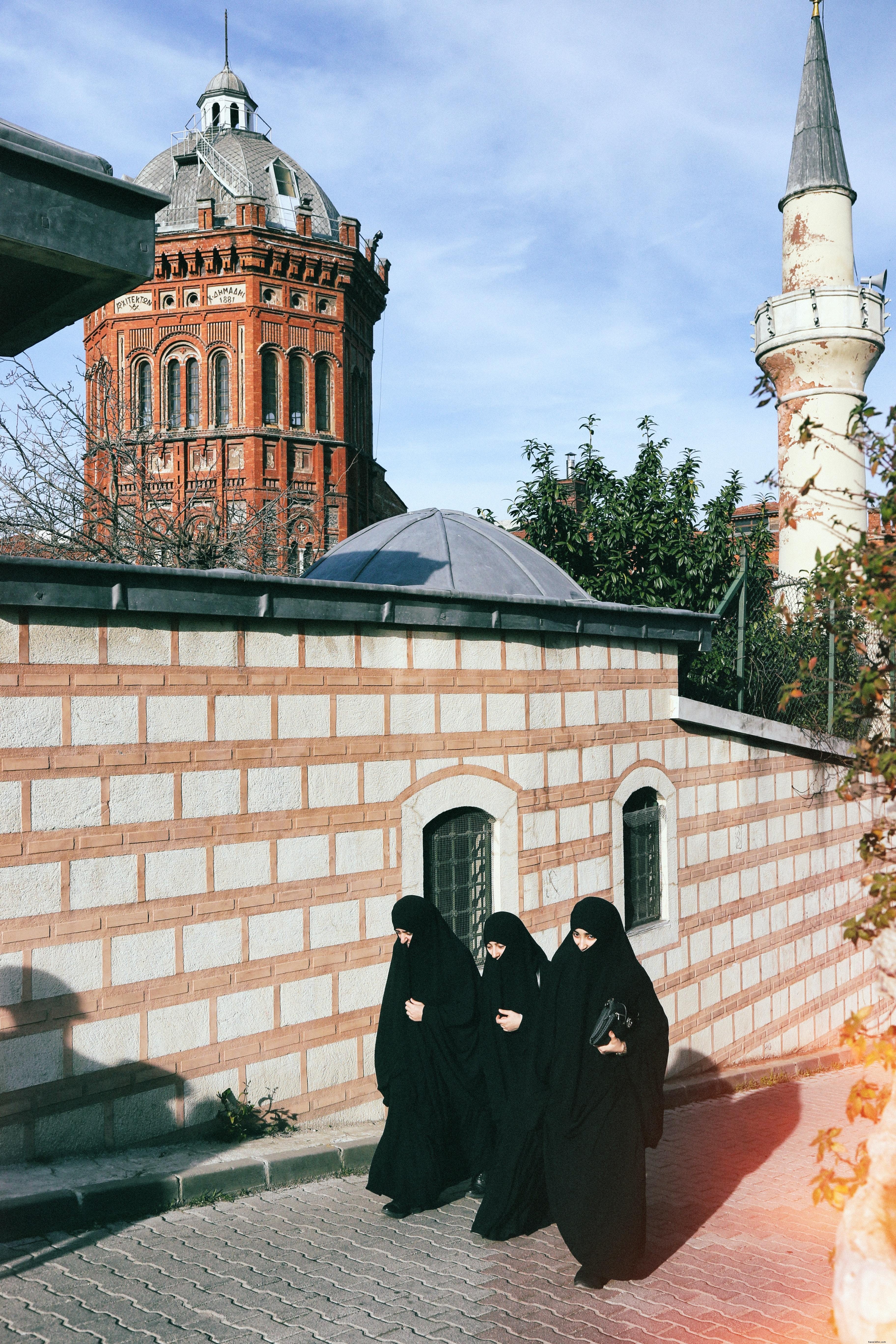 Trois personnes en noir marchent ensemble dans une rue de la ville Photo 