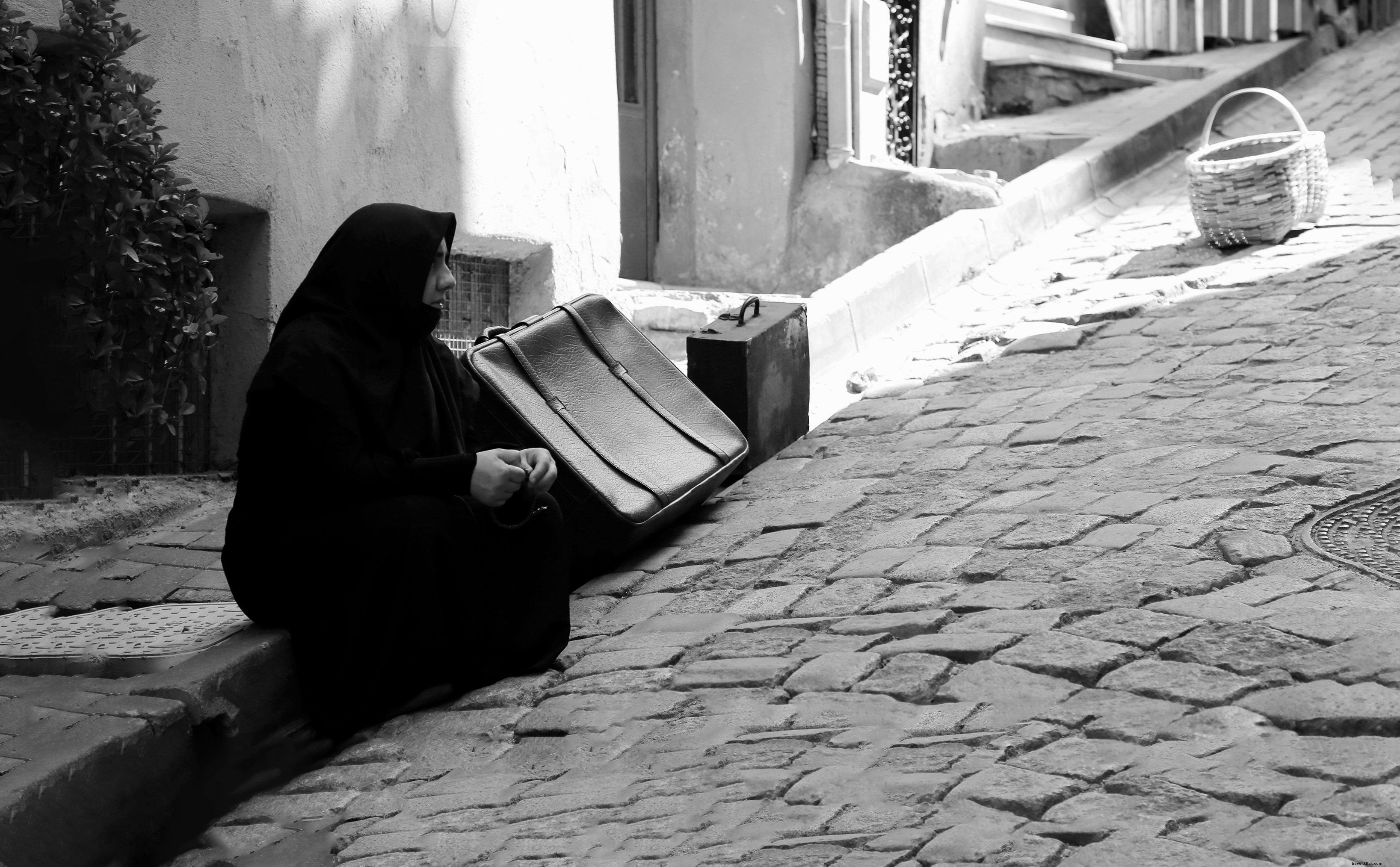 La persona se sienta en la acera junto a las maletas Foto 