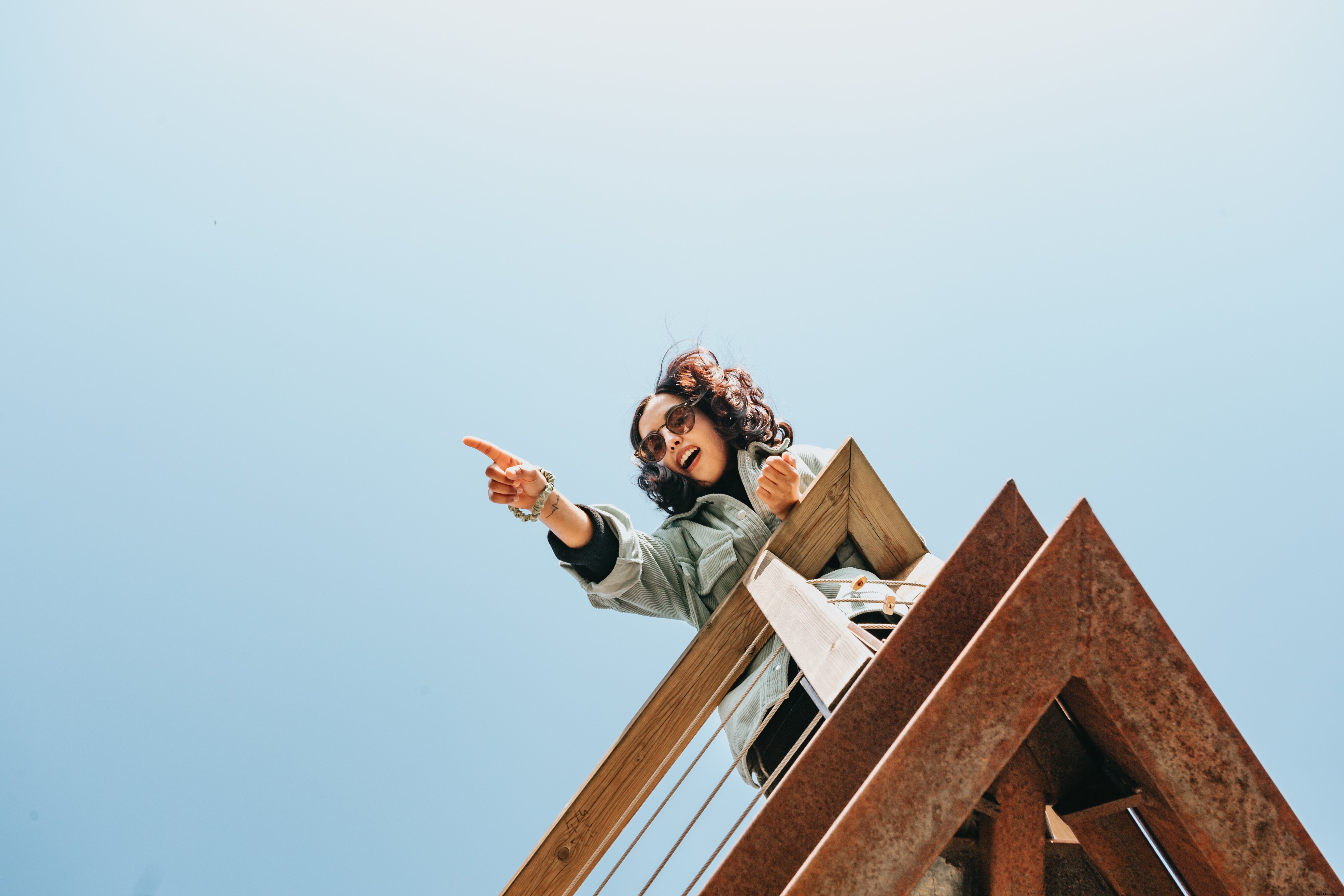 Femme sur une terrasse en bois pointe vers quelque chose hors du cadre photo 