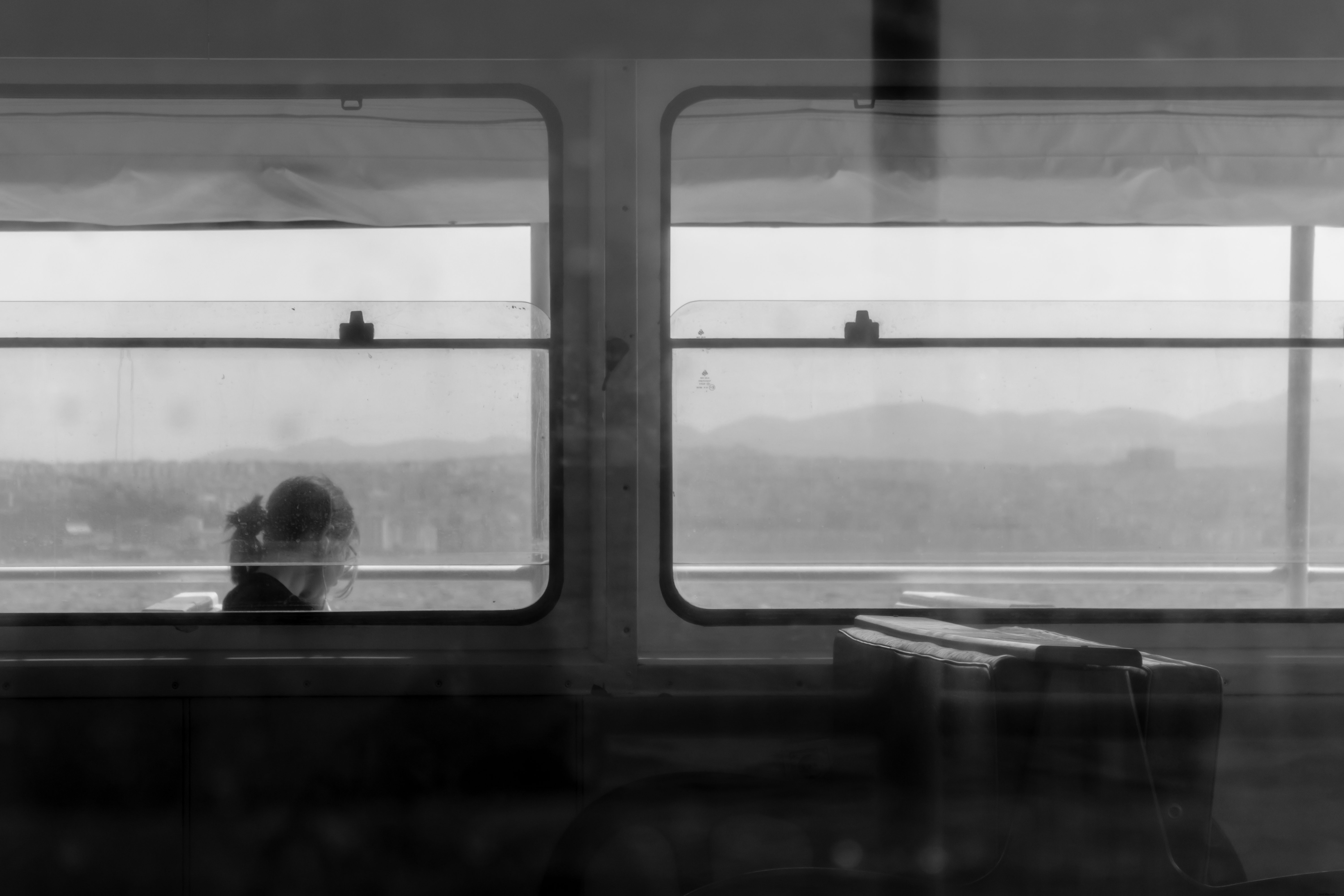 Foto in bianco e nero di una persona seduta alla finestra 