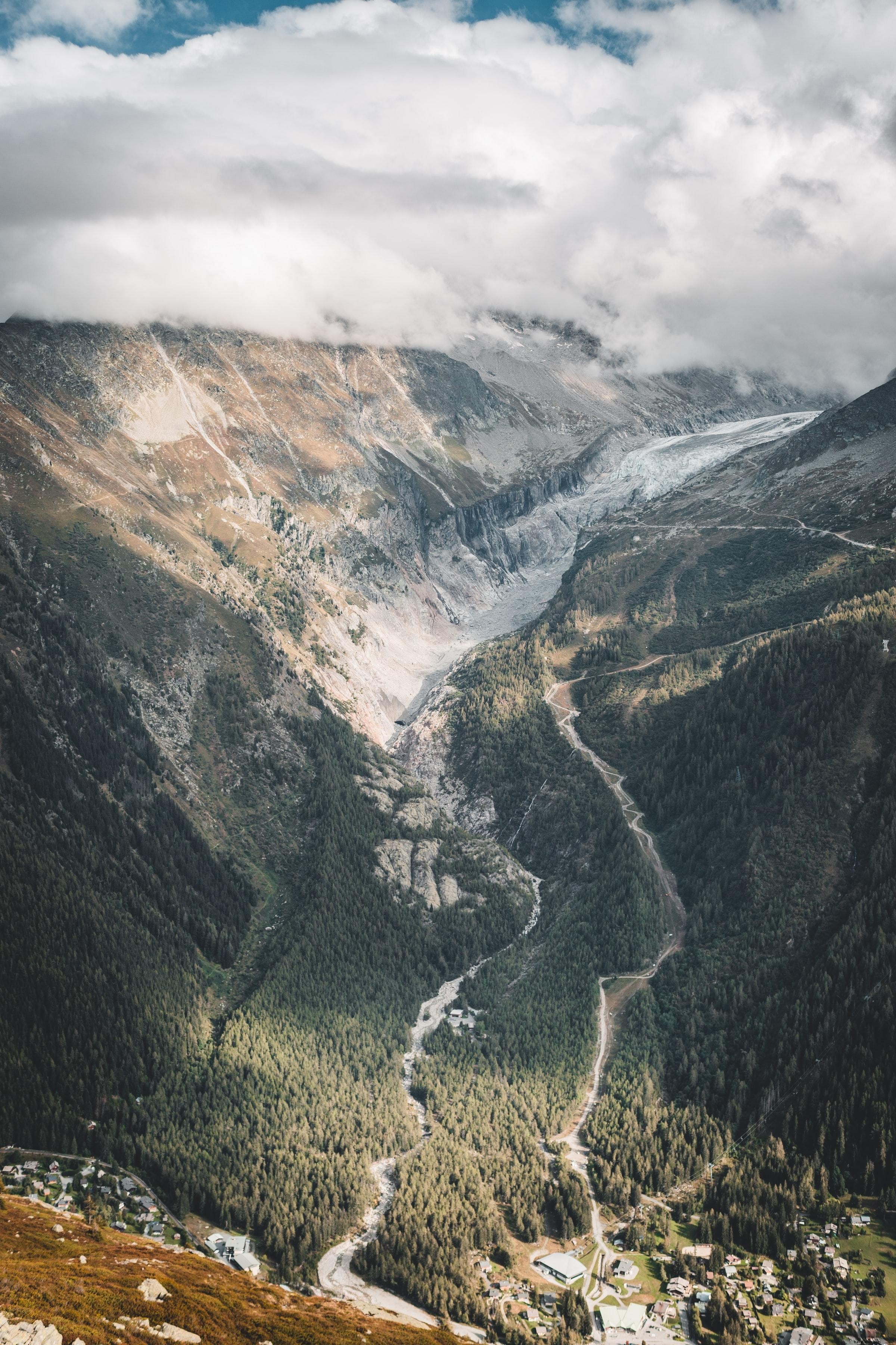 Um vale de montanha ladeado por árvores e uma foto de estrada branca 
