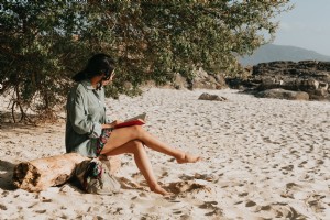 Personne lit son roman assis sur une photo de plage de sable 