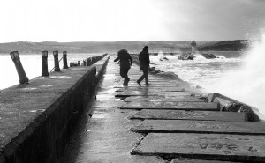 Deux personnes marchant par Choppy Ocean Tide en photo monochrome 