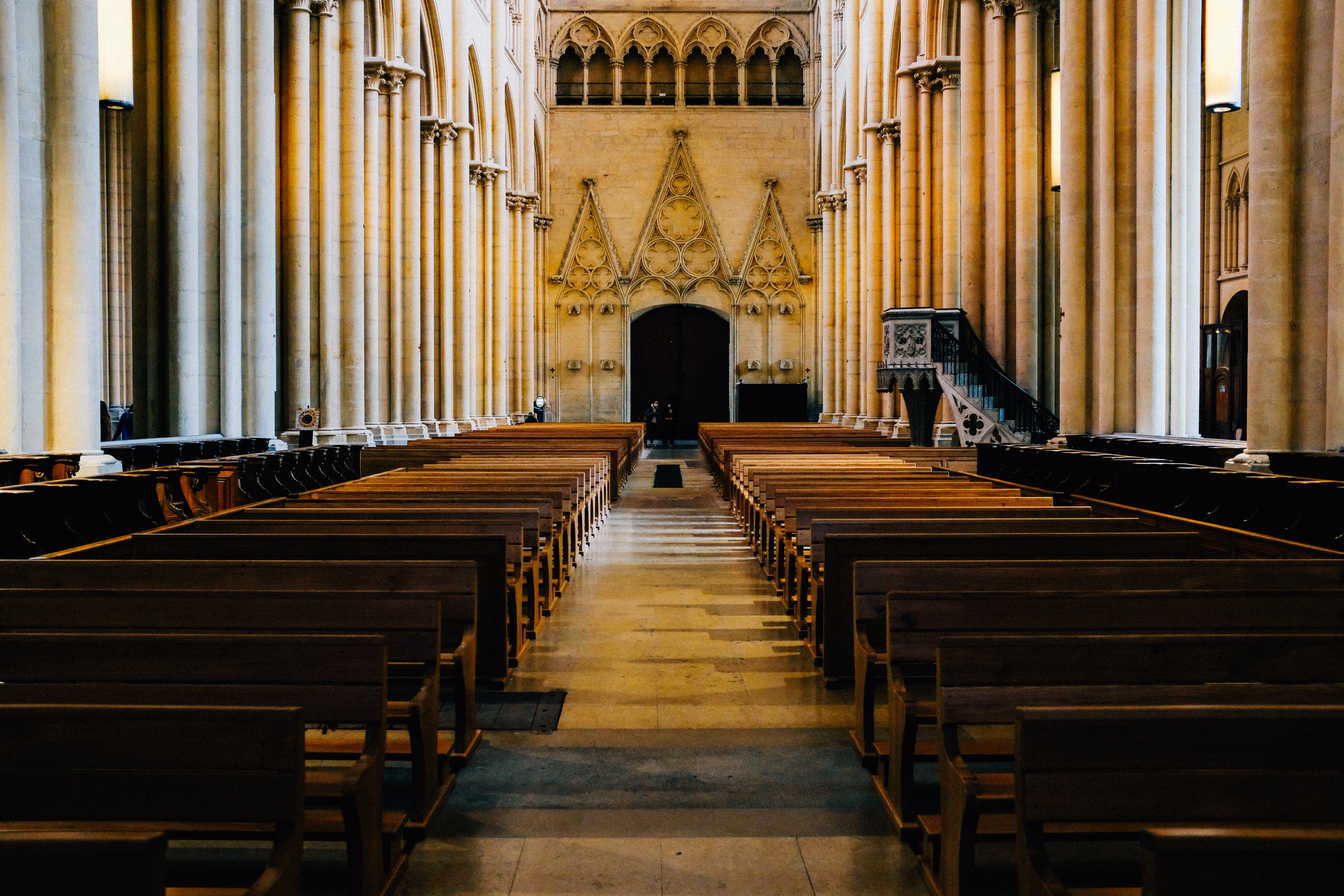 Foto do interior de uma igreja com bancos no corredor 