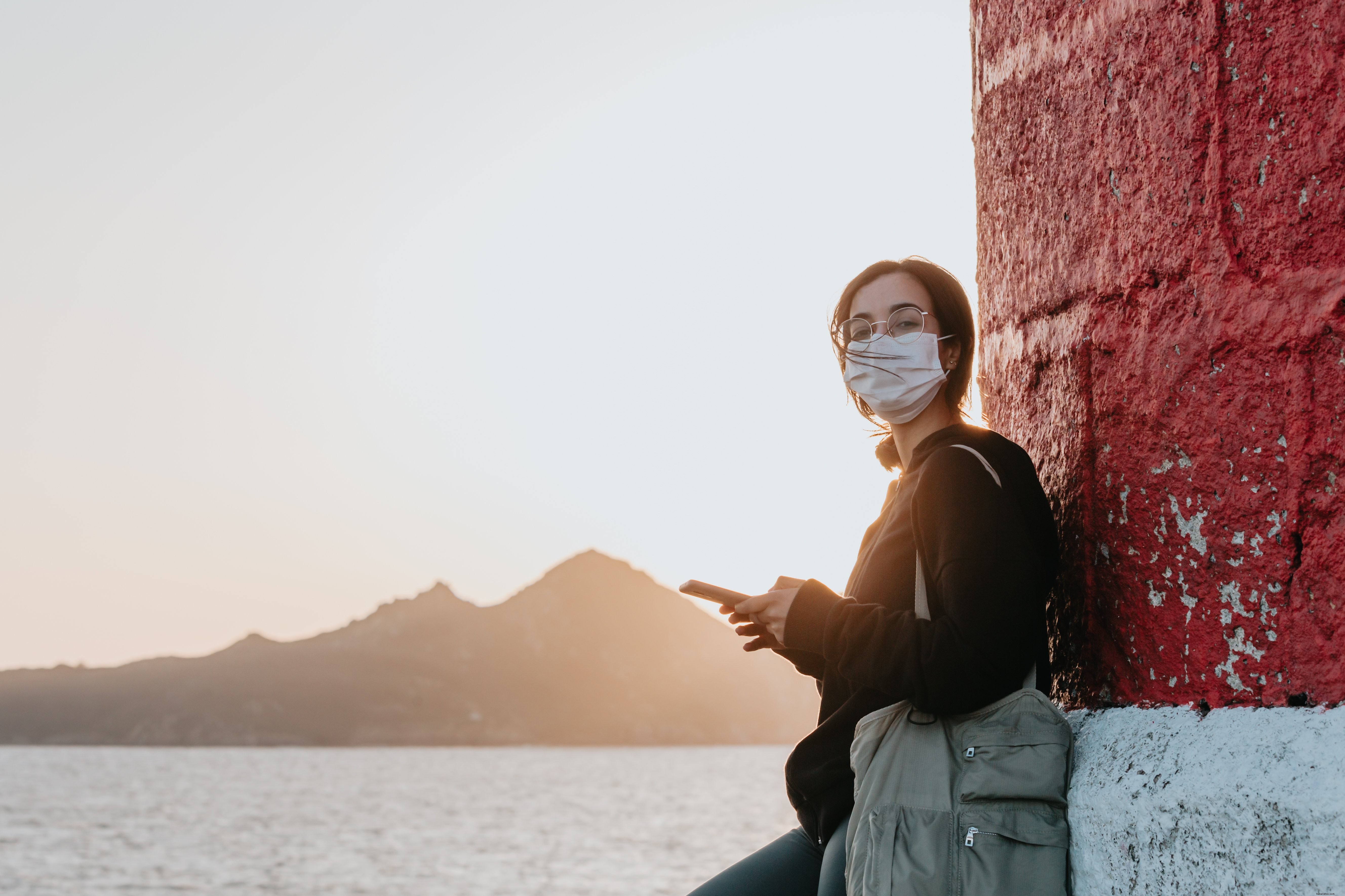 Donna in maschera si appoggia a un muro vicino all acqua Photo 