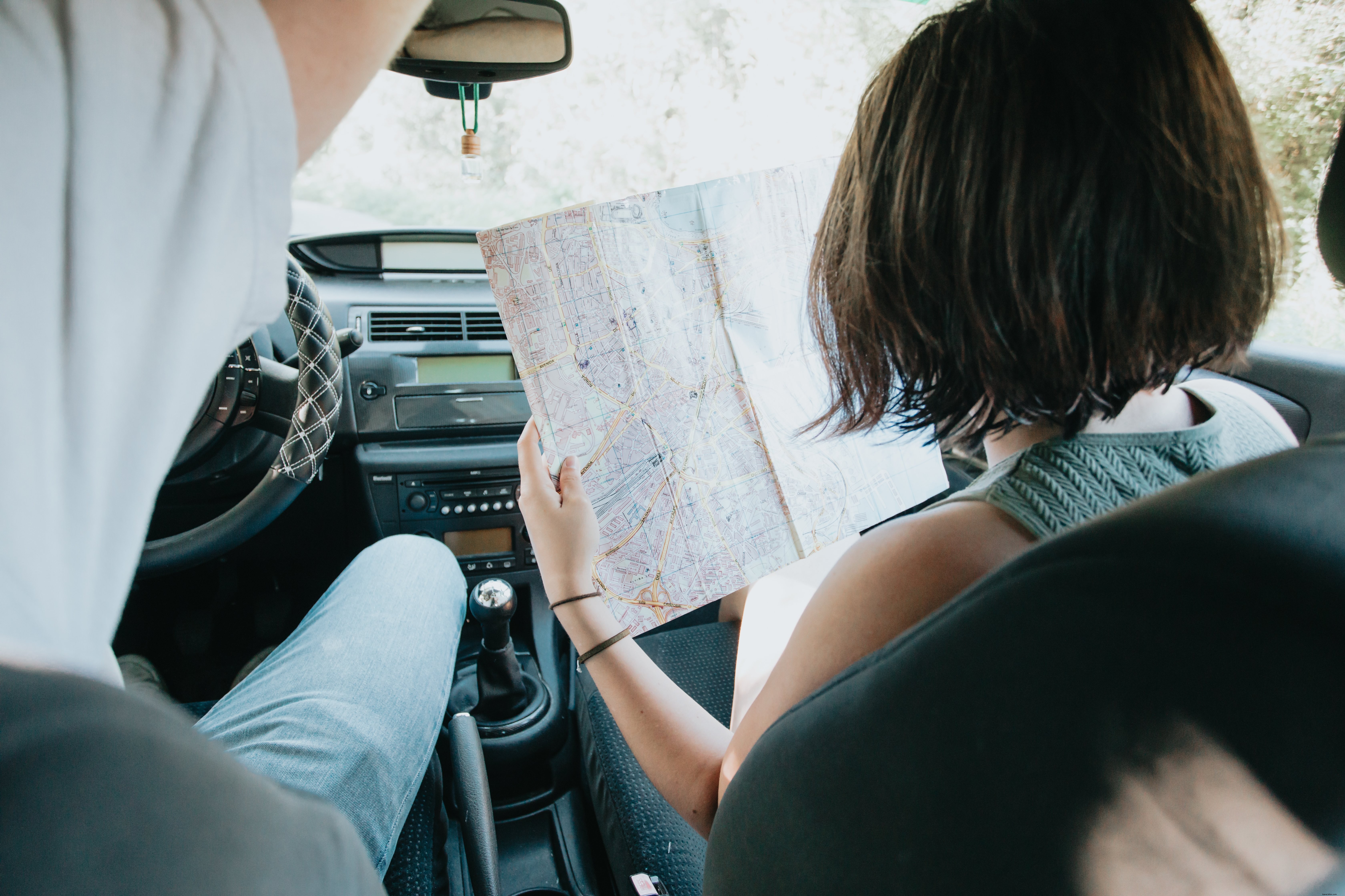 Dos personas en un automóvil con un mapa grande sostenido foto 