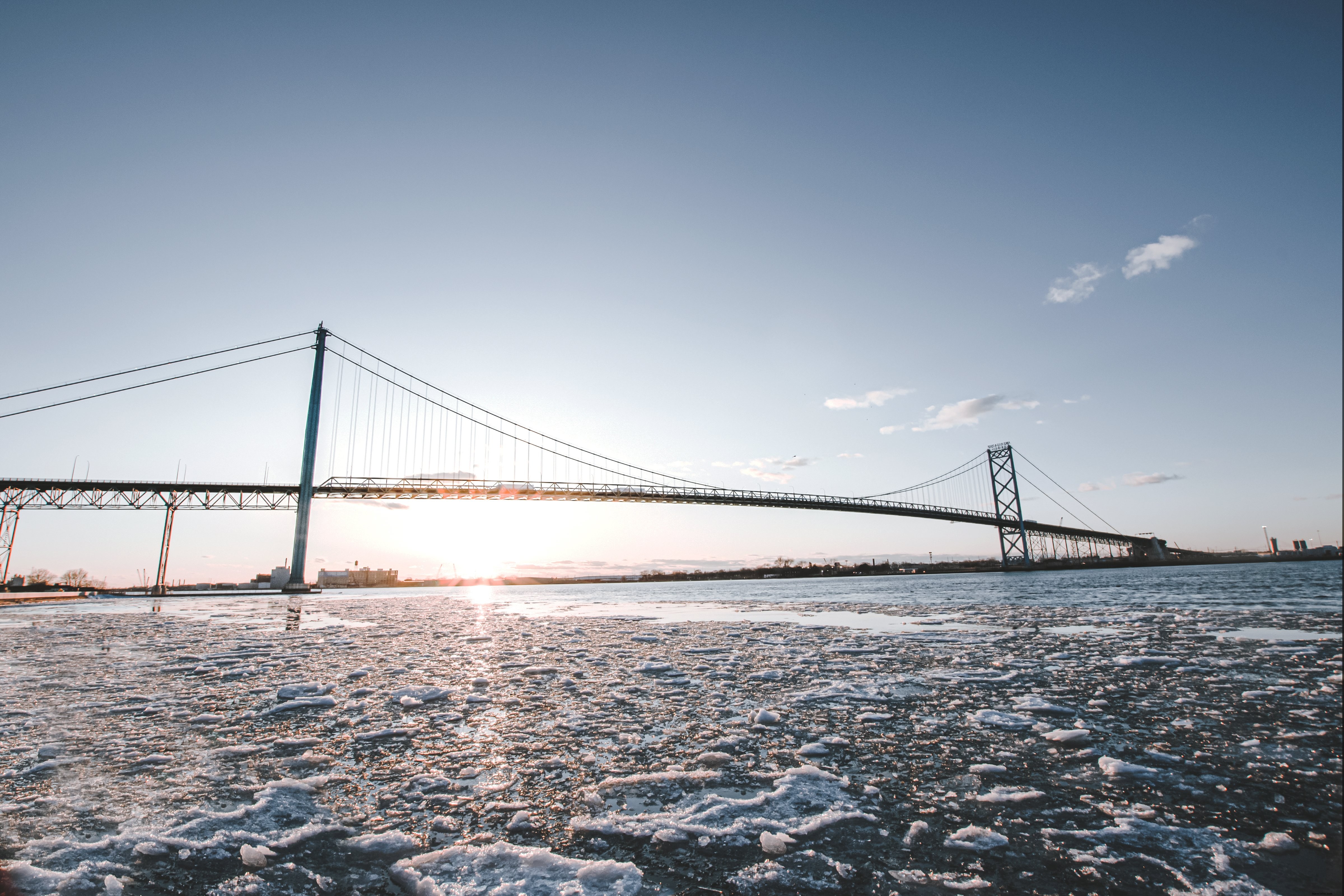 O sol se põe atrás de uma longa ponte de metal no inverno. Foto 