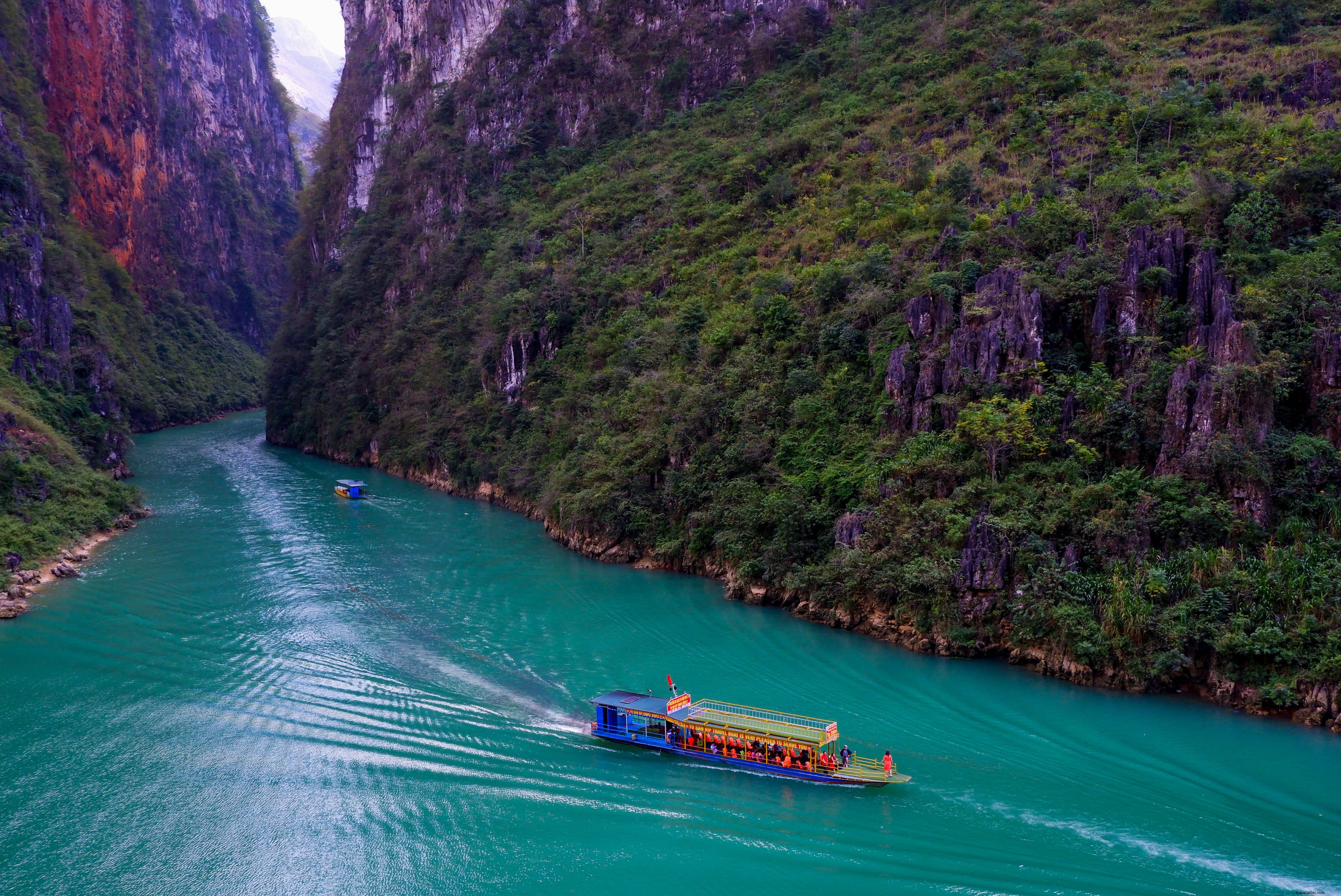 ボートは甘美な緑の山々の間の川に沿って移動します写真 