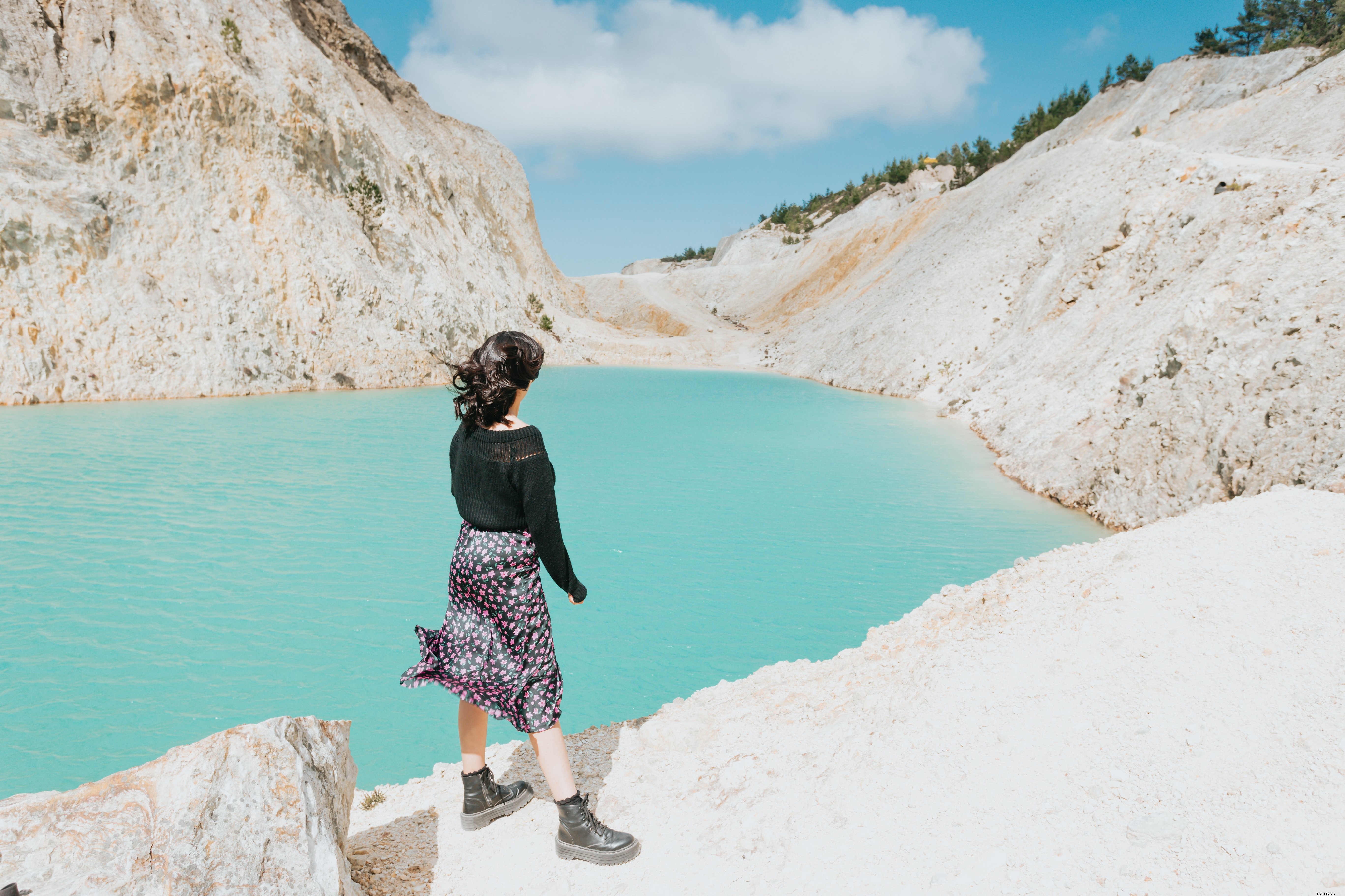 まだ青い水の湖のそばに人が立っている写真 