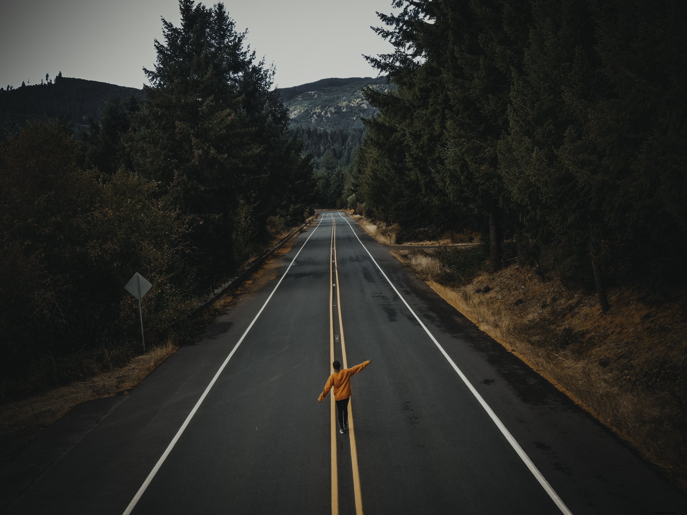 Foto de pessoa caminhando por uma estrada rural pavimentada 