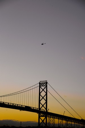 シルエットの大きな橋と日没時のヘリコプター写真 