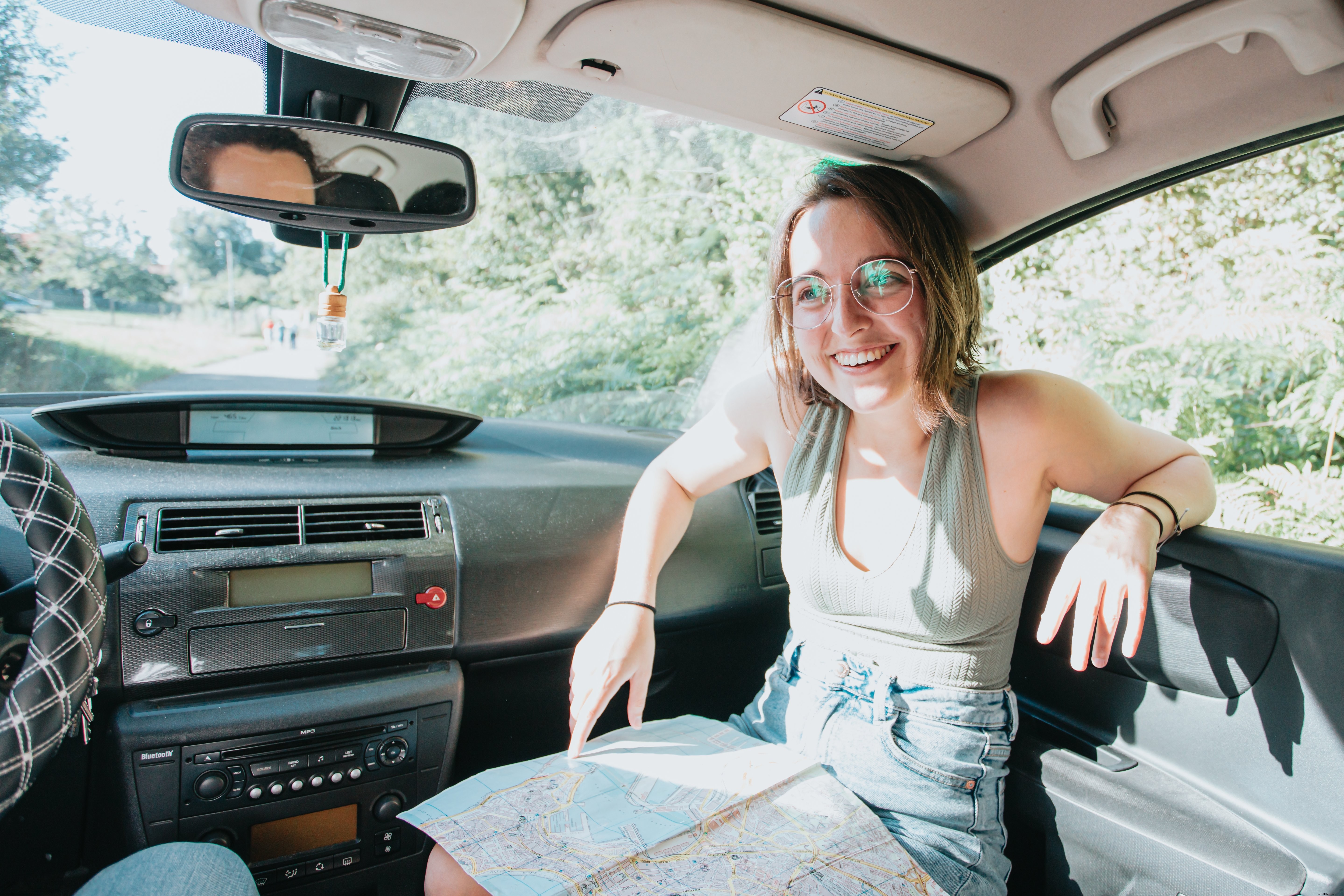 Mujer sonríe en el coche con un mapa en su regazo Foto 