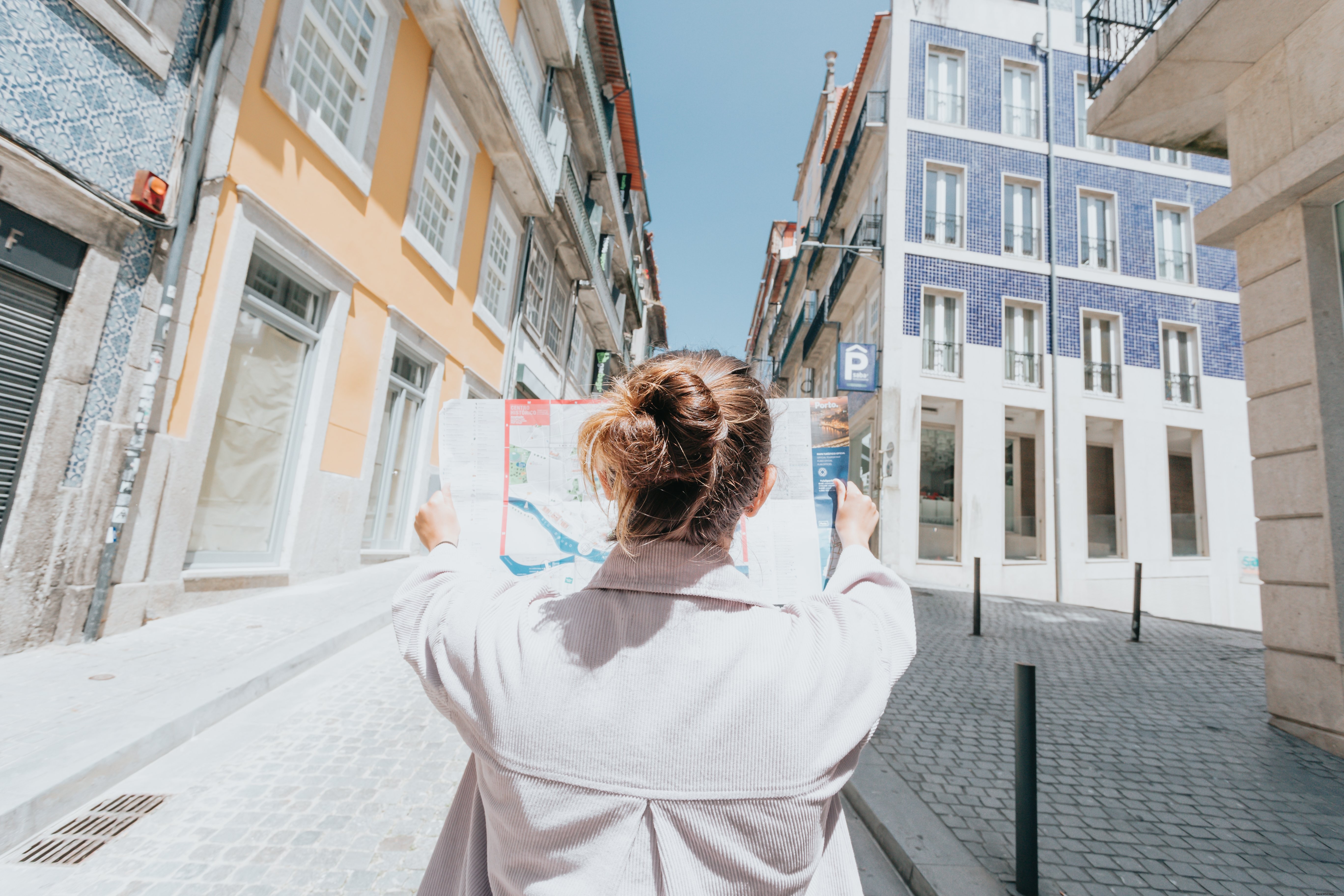 Persona sostiene un mapa mientras está de pie en una foto de una calle de la ciudad 