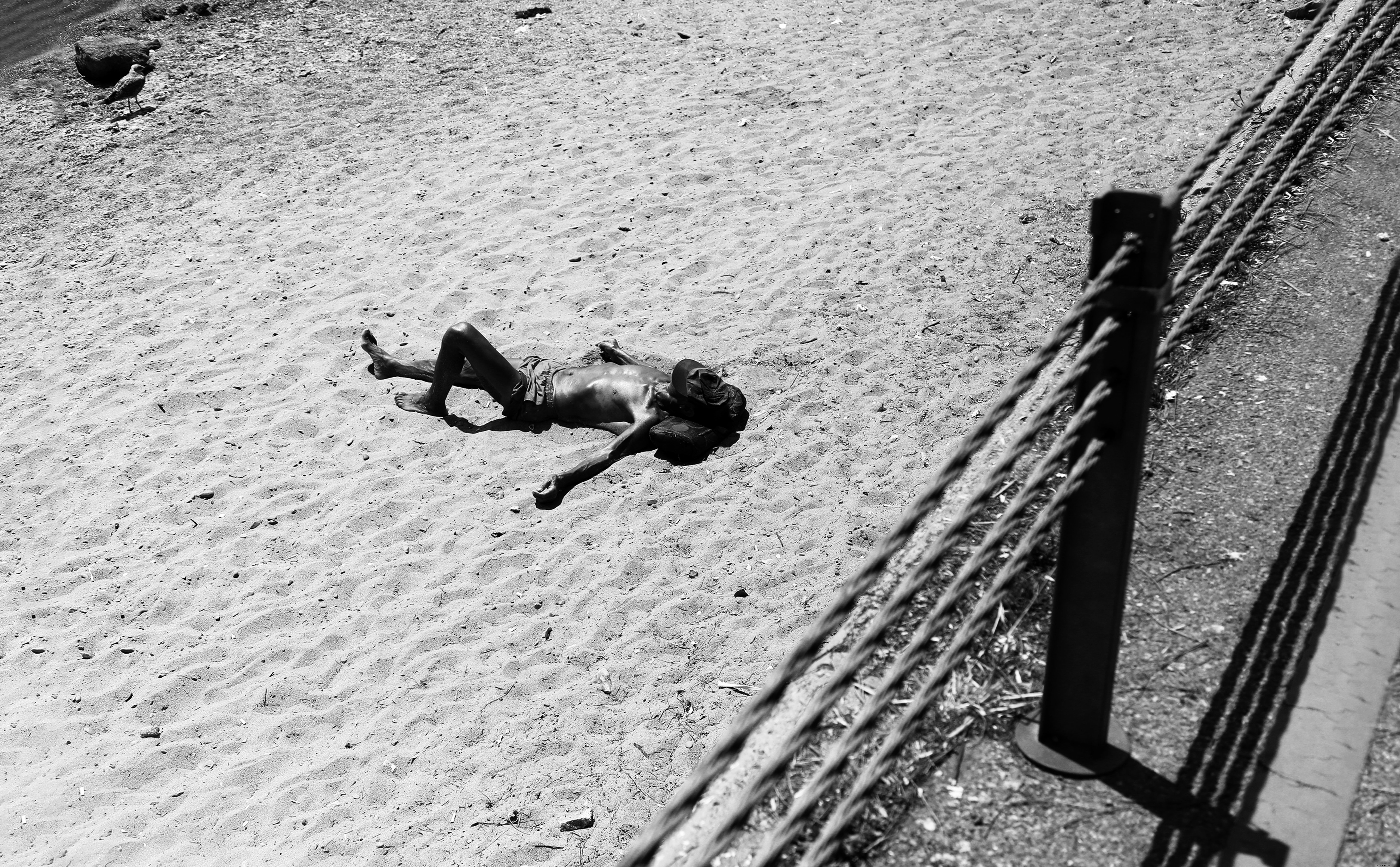 Une personne allongée dans le sable avec un chapeau sur le visage Photo 