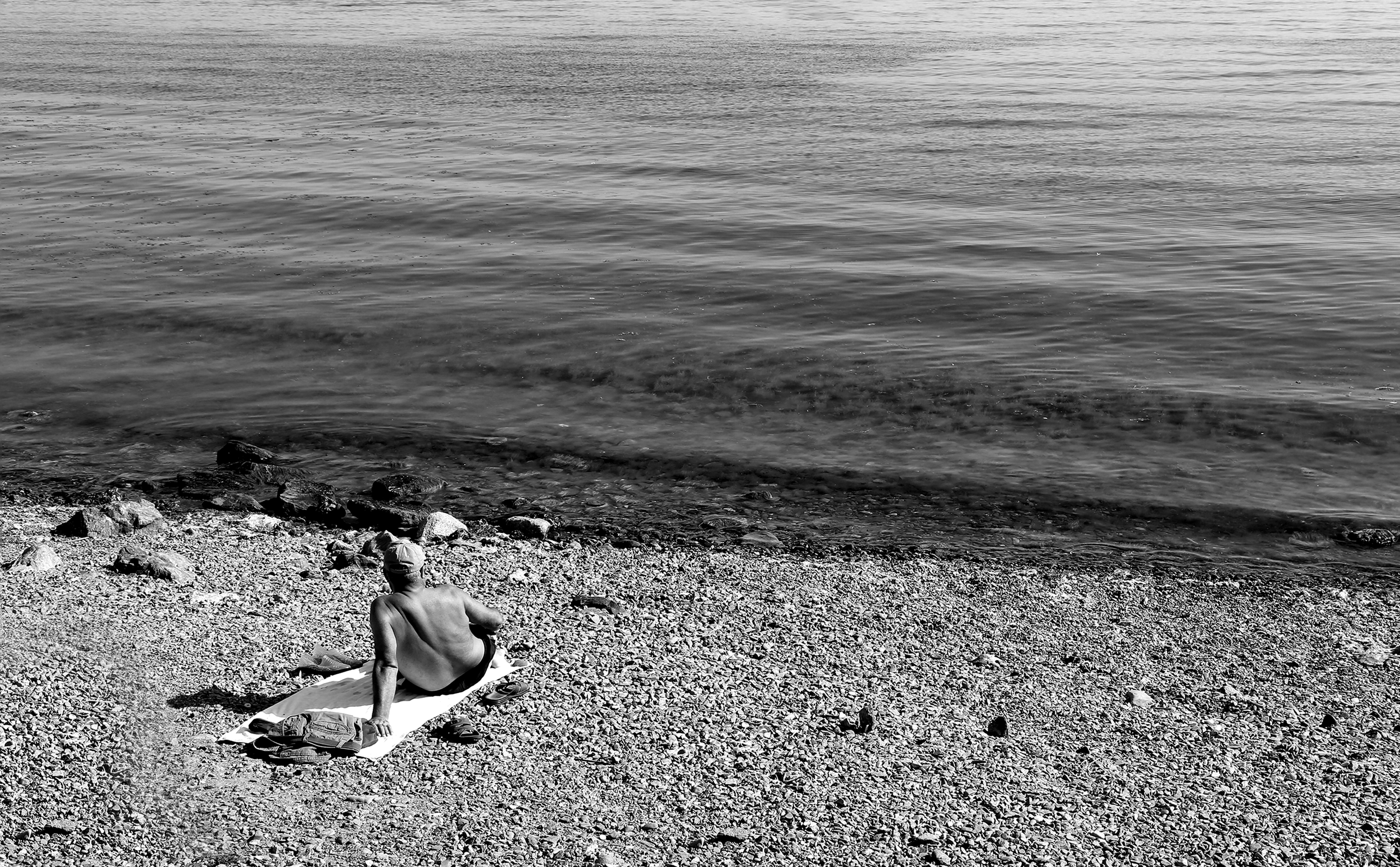 黒と白の写真で彼らのビーチタオルで休んでいる人 