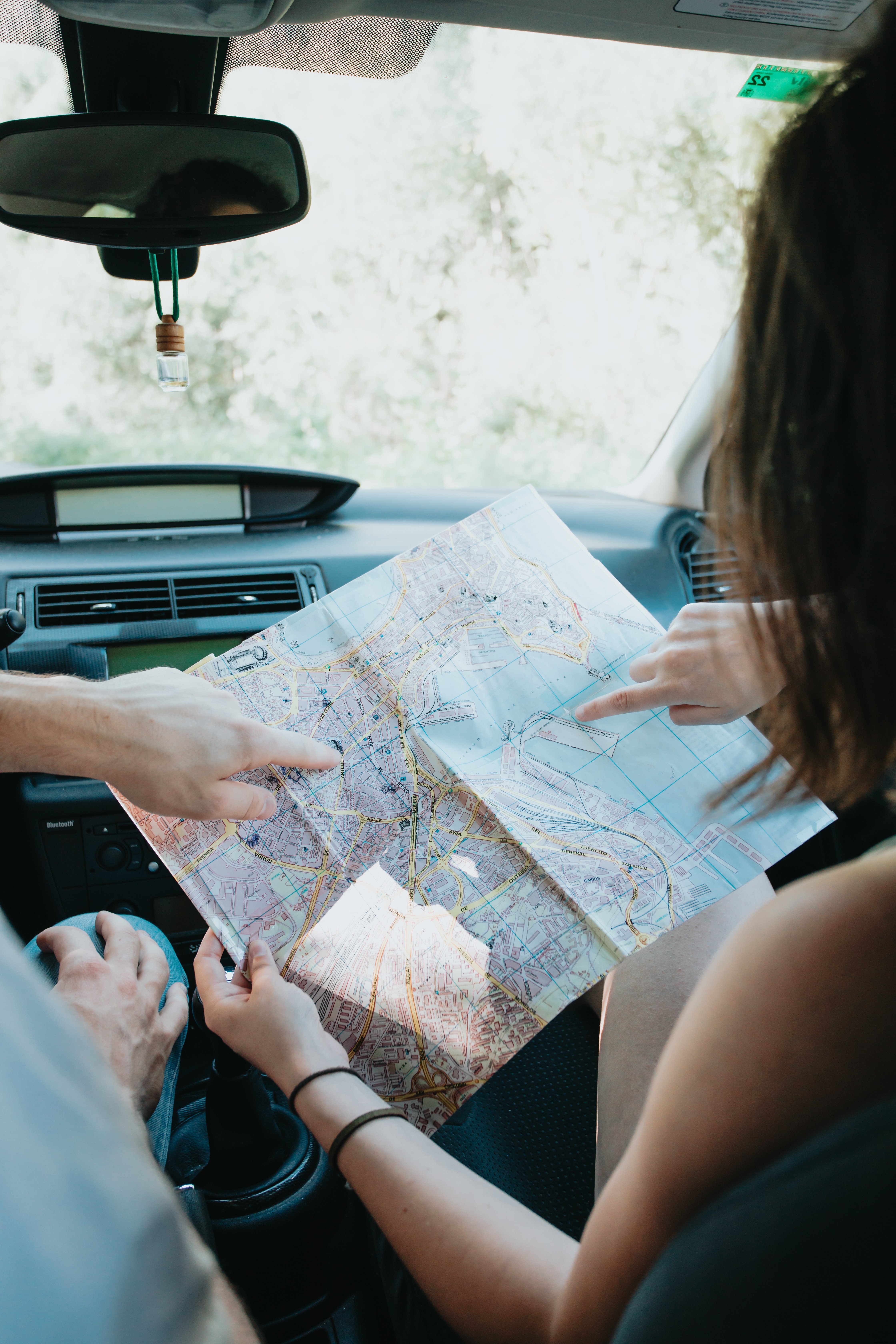 Manos de dos personas sostienen un mapa en una foto de coche 
