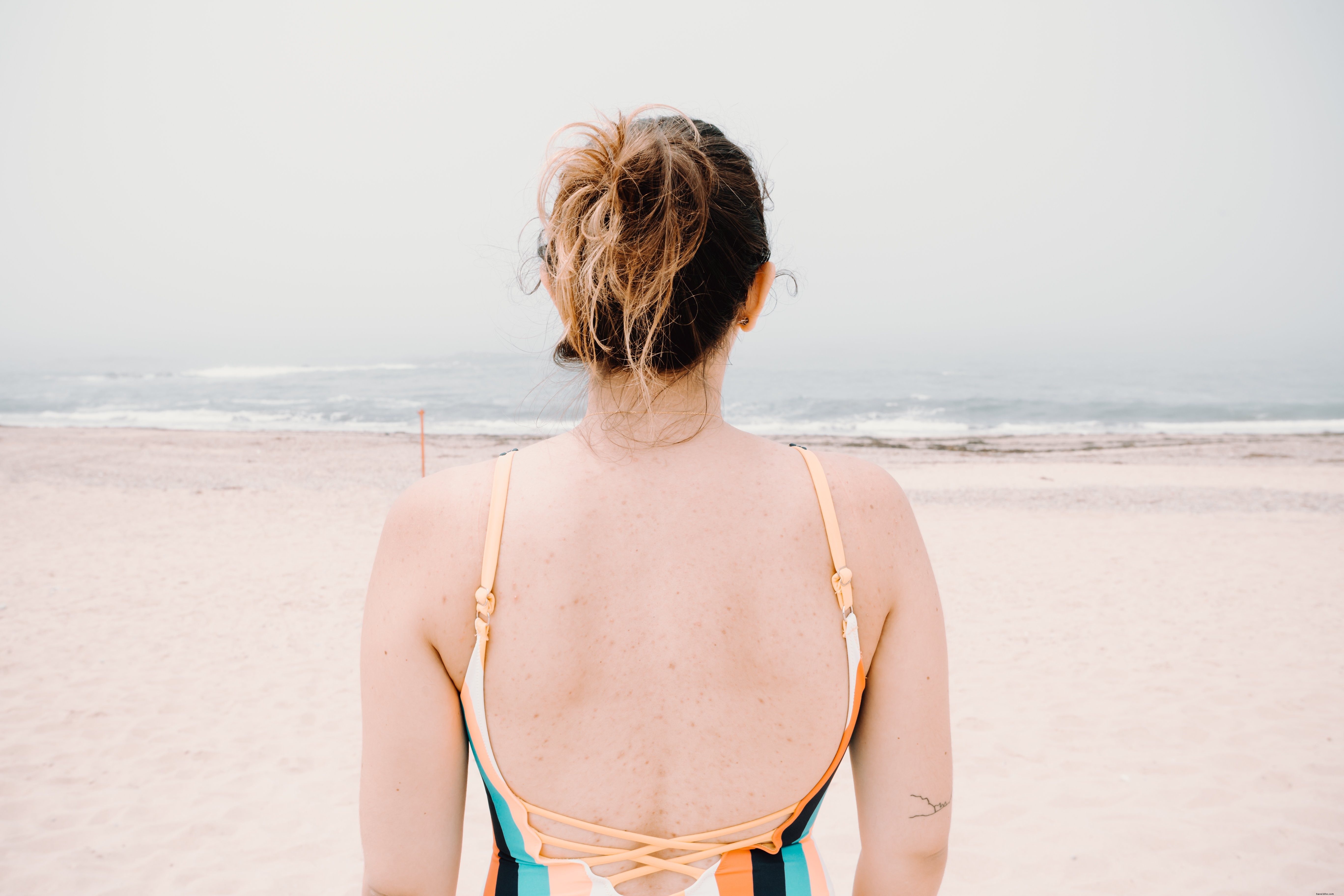 Foto de pessoa enfrentando ondas onduladas em uma praia de areia 
